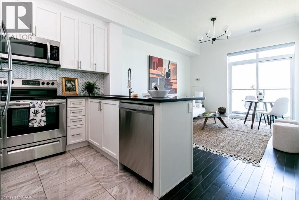 Modern kitchen featuring stainless steel appliances, white cabinetry, black countertops, and a herringbone tile backsplash - 101 Shoreview Place Unit# 631, Stoney Creek, ON - Indoor Photo Showing Kitchen