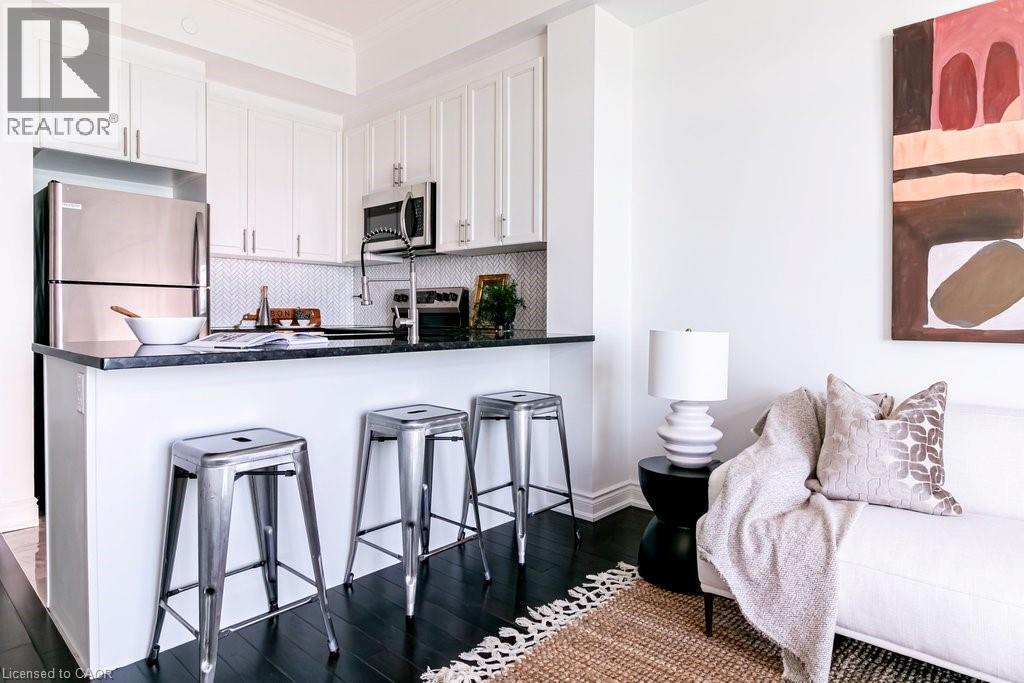 Kitchenette featuring white cabinetry, stainless steel appliances, dark countertops, and a white herringbone tile backsplash - 101 Shoreview Place Unit# 631, Stoney Creek, ON - Indoor Photo Showing Other Room