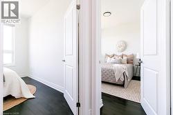 Interior doors with paneled detailing open to rooms featuring dark wood-finish flooring, white baseboards, and bright white walls -