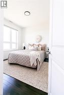 Spacious room featuring dark wood-finish flooring, a contemporary flush-mount ceiling light, and a large window with white framing -