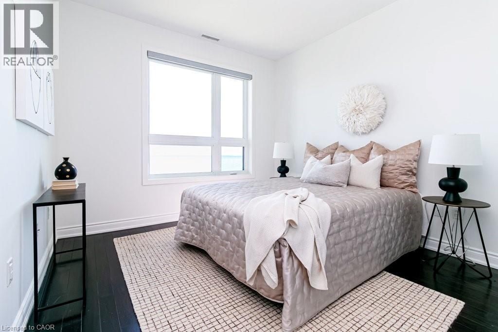 Bright room featuring a large picture window, dark wood-finish flooring, white baseboards, and white walls - 101 Shoreview Place Unit# 631, Stoney Creek, ON - Indoor Photo Showing Bedroom