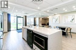 Spacious communal area featuring a kitchen island with stone countertop and integrated sink, light wood-finish flooring, recessed lighting, and expansive windows -