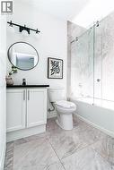 Contemporary bathroom featuring a white vanity with black countertop, a round mirror, and a three-light matte black fixture -