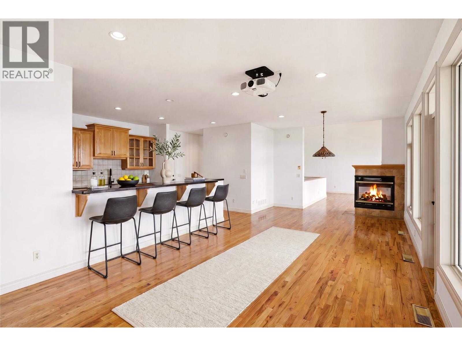 Virtually staged with barstools and furniture - 448 Viewcrest Road, Kelowna, BC - Indoor With Fireplace