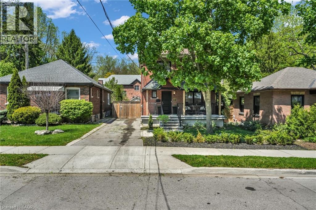 Brick-clad residence featuring a covered front porch with dark railings and stone steps - 25 Park Street E, Hamilton, ON - Outdoor