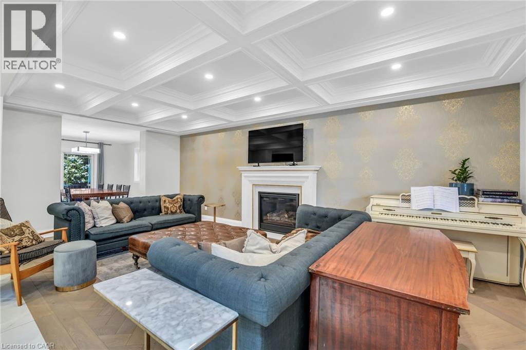 Coffered ceilings with recessed lighting, wood-finish herringbone flooring, a white mantel fireplace, and a feature wall with metallic pattern - 25 Park Street E, Hamilton, ON - Indoor Photo Showing Living Room With Fireplace