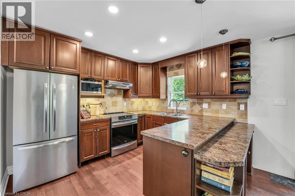Kitchen featuring wood-finish cabinetry, stainless steel appliances, and wood-finish flooring - 25 Park Street E, Hamilton, ON - Indoor Photo Showing Kitchen With Double Sink