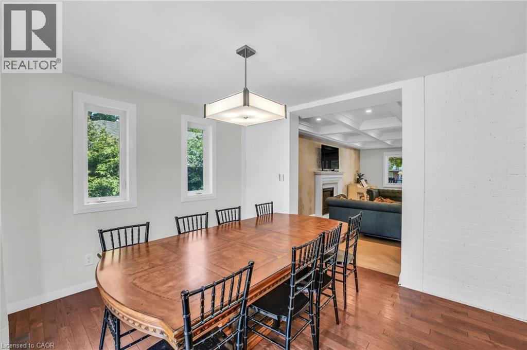 Dining area featuring rich wood-finish flooring, two large windows, and a contemporary ceiling light fixture - 25 Park Street E, Hamilton, ON - Indoor Photo Showing Dining Room