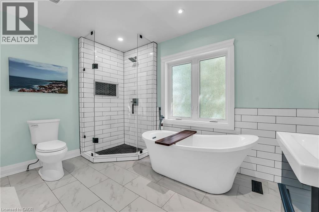 Bathroom featuring a freestanding soaking tub, a glass-enclosed shower with subway tile surround, a built-in shower niche, and a contemporary vanity with a rectangular sink - 25 Park Street E, Hamilton, ON - Indoor Photo Showing Bathroom