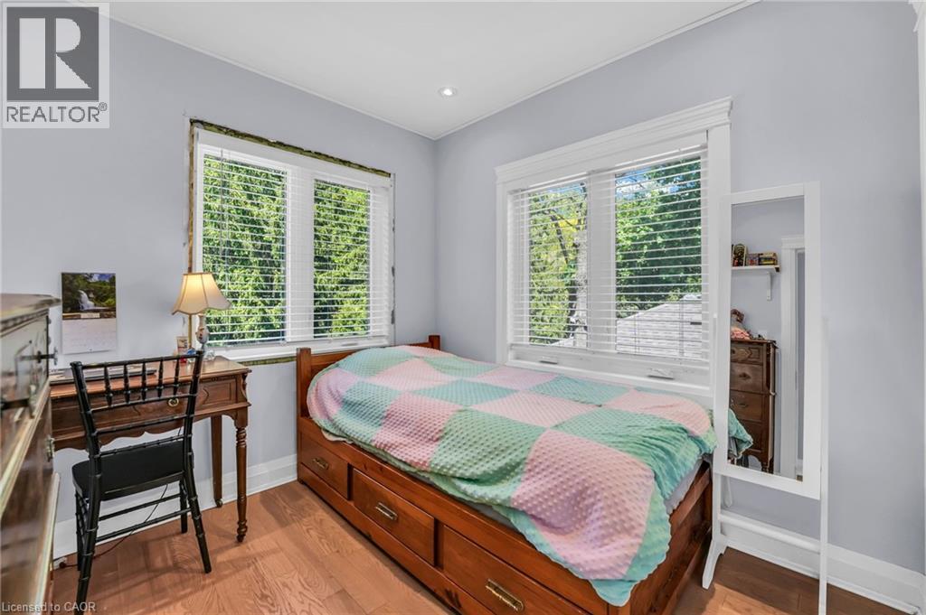 Light blue painted walls compliment the wood-finish flooring - 25 Park Street E, Hamilton, ON - Indoor Photo Showing Bedroom