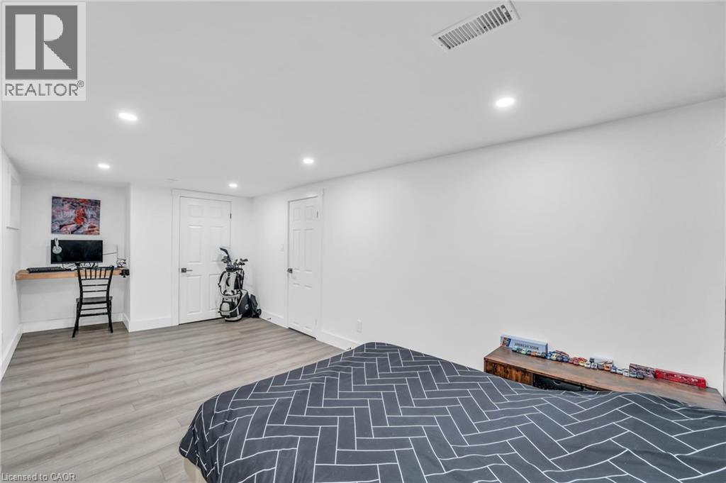 Spacious room featuring wood-finish flooring, recessed lighting, and white paneled doors - 25 Park Street E, Hamilton, ON - Indoor