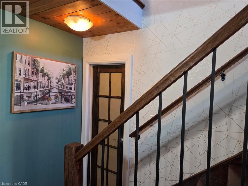 Staircase featuring dark wood handrails, black metal balusters, and geometric pattern wall covering - 112 Indian Road, Asphodel-Norwood Twp, ON - Indoor Photo Showing Other Room