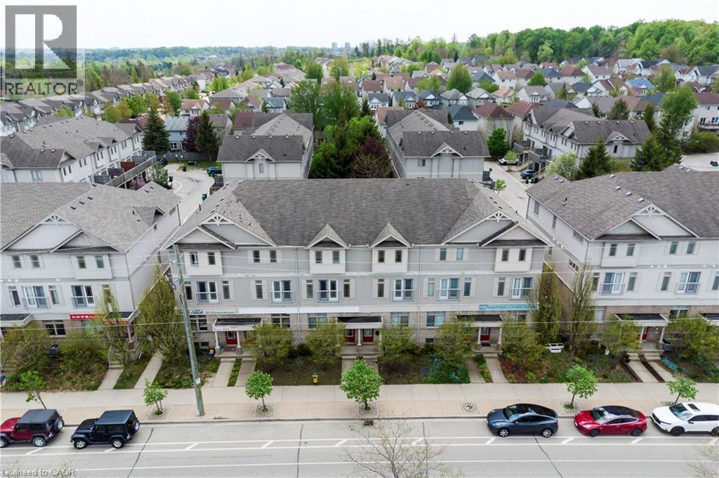 Contemporary townhome exterior featuring light gray siding, dark gray shingle roofing, and red entry doors - 619 Wild Ginger Avenue Unit# C15, Waterloo, ON - Outdoor With Facade