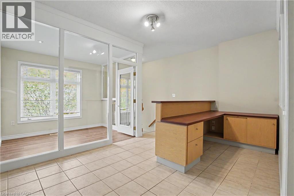 Tile flooring in main area, with a built-in desk featuring a wood-finish countertop and light wood-finish cabinetry - 619 Wild Ginger Avenue Unit# C15, Waterloo, ON - Indoor Photo Showing Other Room