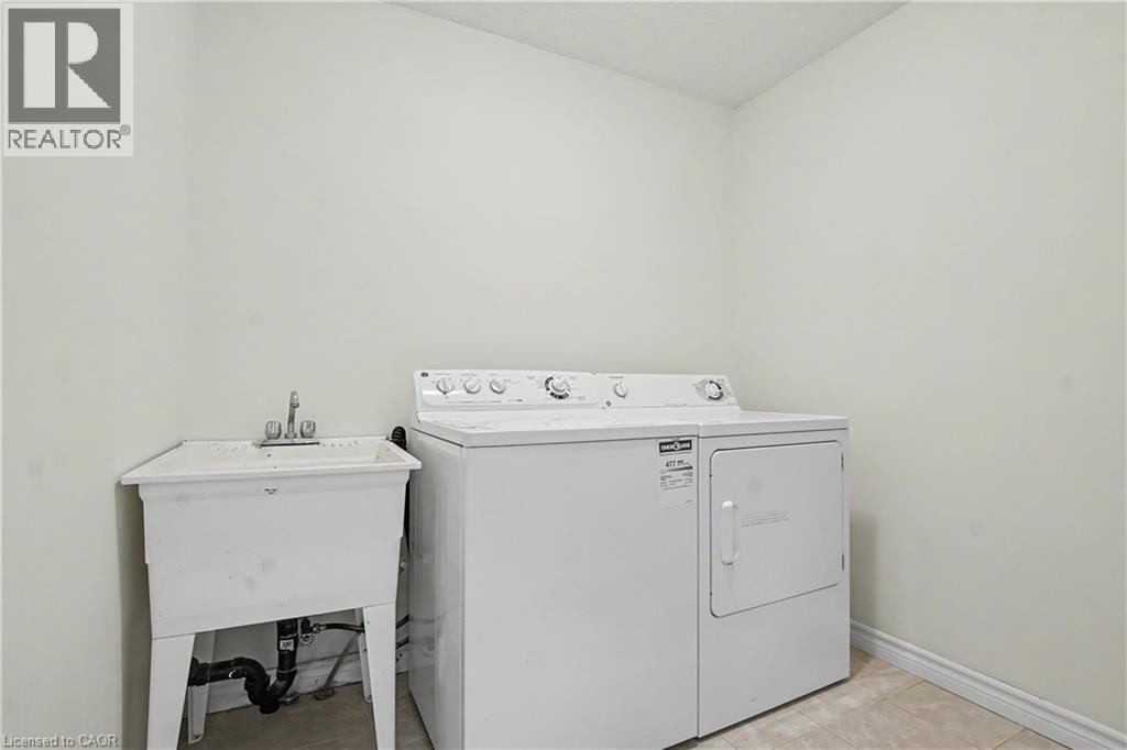 Dedicated laundry space with a utility sink, a top-loading washing machine, and a front-loading dryer - 619 Wild Ginger Avenue Unit# C15, Waterloo, ON - Indoor Photo Showing Laundry Room