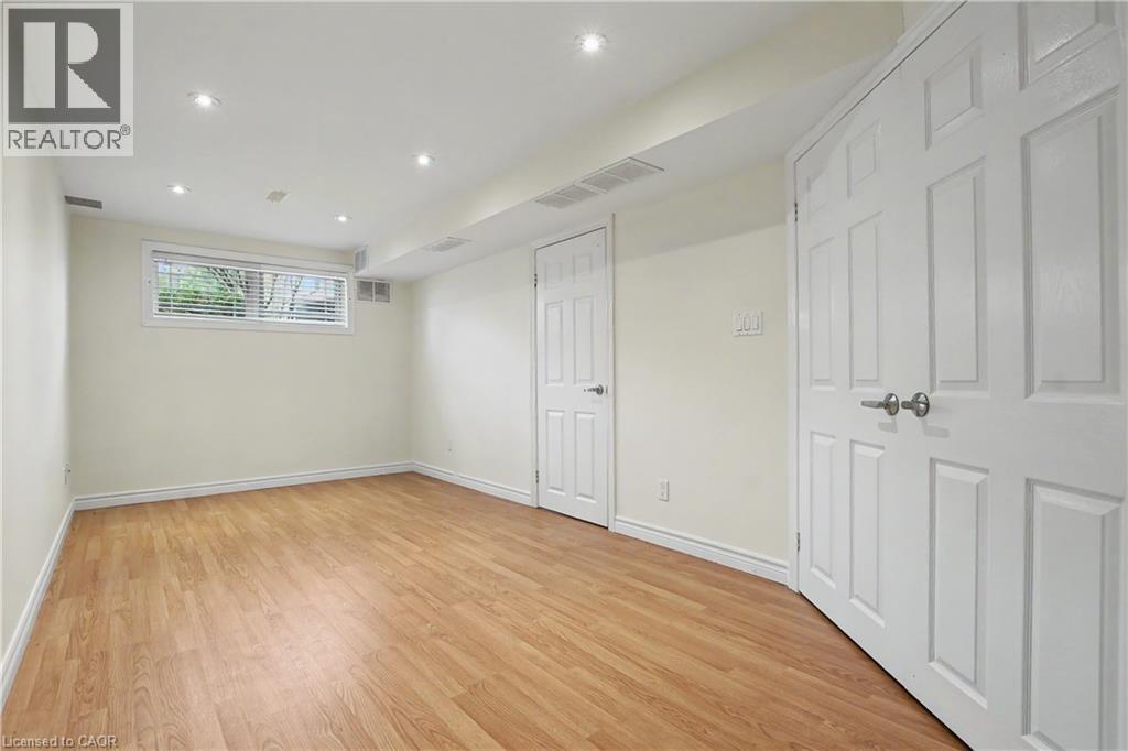Spacious room featuring wood-finish flooring, recessed lighting, and a white trim package - 619 Wild Ginger Avenue Unit# C15, Waterloo, ON - Indoor Photo Showing Other Room