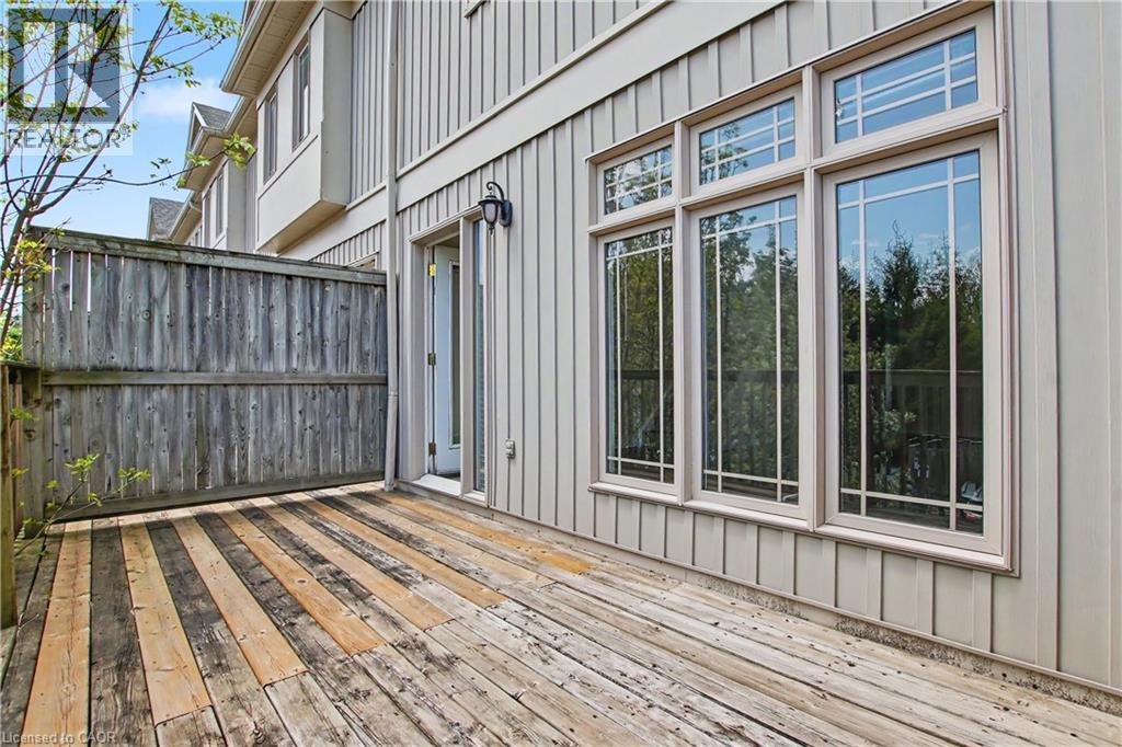 Private wooden deck featuring a privacy fence, exterior light fixture, and triple paned windows - 619 Wild Ginger Avenue Unit# C15, Waterloo, ON - Outdoor With Deck Patio Veranda With Exterior
