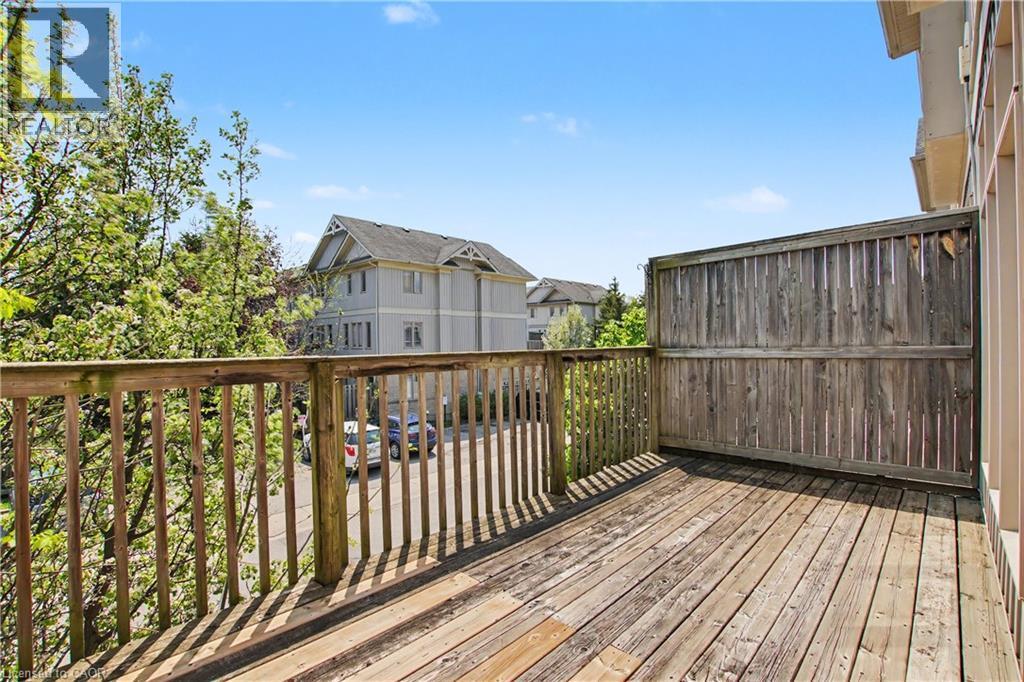 Outdoor wooden deck with a privacy fence, baluster railing, and natural light exposure - 619 Wild Ginger Avenue Unit# C15, Waterloo, ON - Outdoor With Exterior