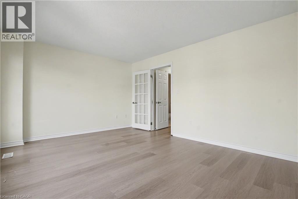 Spacious room featuring wood-finish flooring, white baseboards, and neutral wall paint - 619 Wild Ginger Avenue Unit# C16, Waterloo, ON - Indoor Photo Showing Other Room