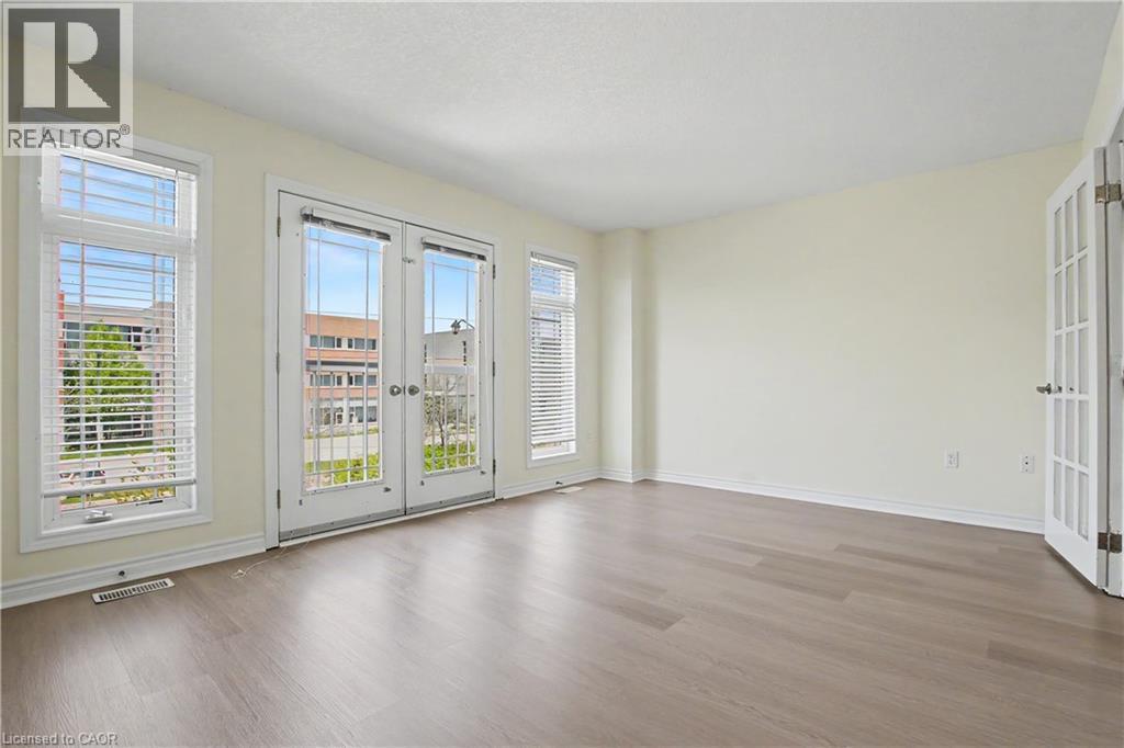 Spacious room featuring wood-finish flooring, light-toned walls, and a white ceiling - 619 Wild Ginger Avenue Unit# C16, Waterloo, ON - Indoor Photo Showing Other Room