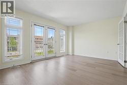 Spacious room featuring wood-finish flooring, light-toned walls, and a white ceiling -