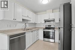 Kitchen featuring white cabinetry, light-toned countertops, a diagonal tile backsplash, stainless steel appliances, and tile flooring -