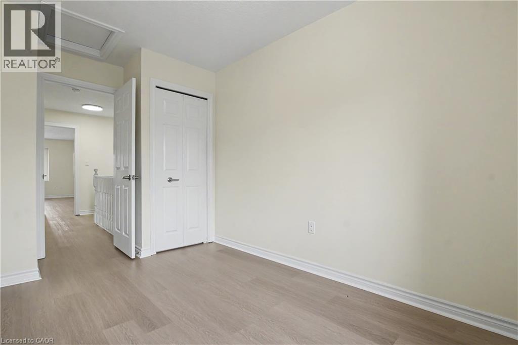 Light wood-finish flooring throughout, complemented by white baseboards and neutral wall tones - 619 Wild Ginger Avenue Unit# C16, Waterloo, ON - Indoor Photo Showing Other Room