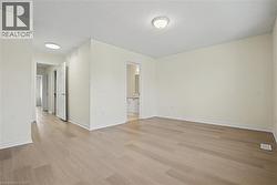 Spacious interior featuring light wood-finish flooring, neutral wall tones, white trim, and flush-mount ceiling lighting -