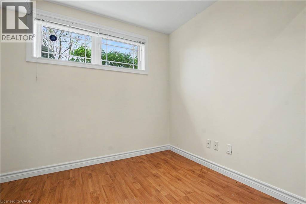 Neutral wall paint with wood-finish flooring and white baseboards - 619 Wild Ginger Avenue Unit# C16, Waterloo, ON - Indoor Photo Showing Other Room