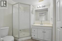 Contemporary bathroom featuring a corner shower with frosted glass enclosure, a white vanity with paneling, a countertop with integrated sink, a rectangular mirror, and overhead vanity lighting -