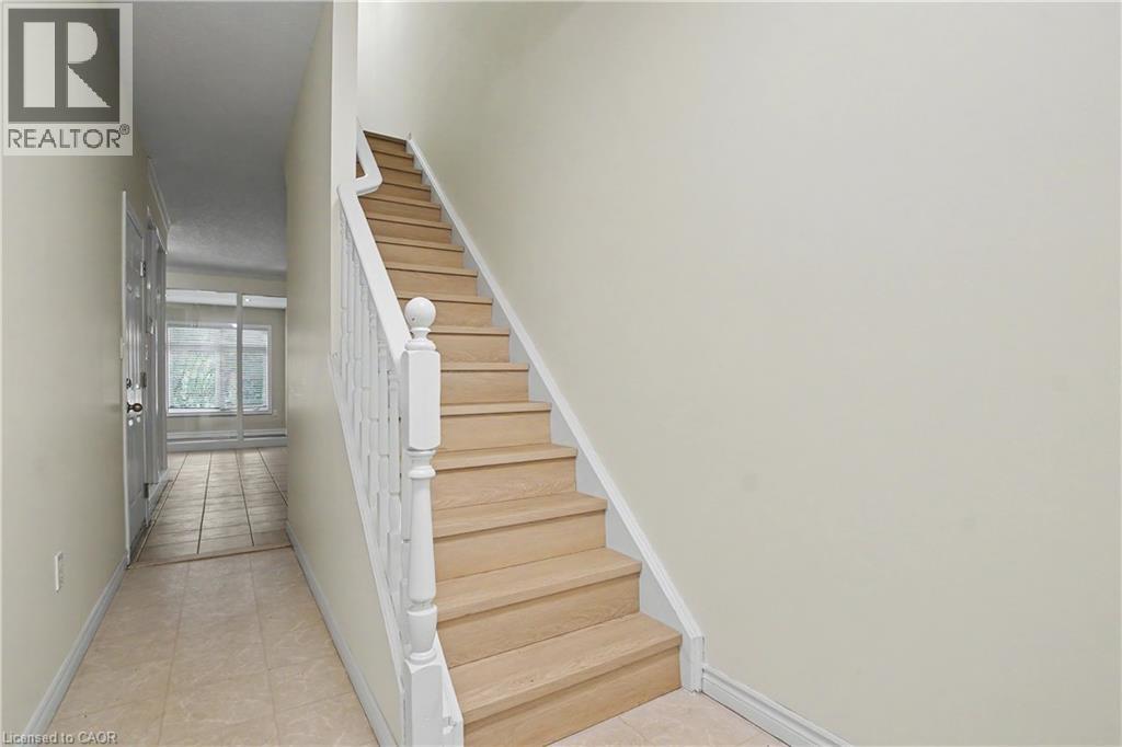 Hardwood stairs with white balusters and newel post - 619 Wild Ginger Avenue Unit# C16, Waterloo, ON - Indoor Photo Showing Other Room