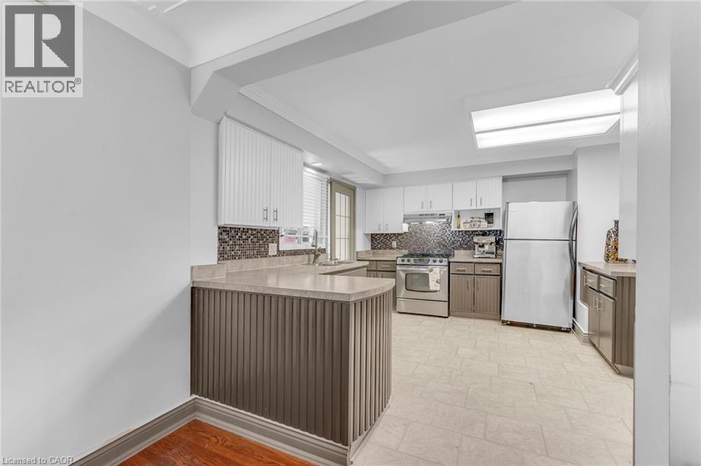 Kitchen featuring a curved breakfast bar with slat paneling, stone countertops, and a mosaic tile backsplash - 1 Galbraith Drive, Hamilton, ON - Indoor Photo Showing Kitchen