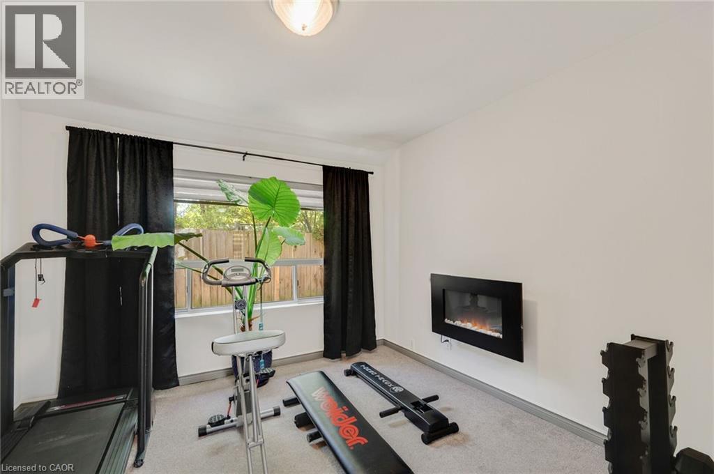 Room with wall-mounted electric fireplace, light gray carpet, and white walls - 1 Galbraith Drive, Hamilton, ON - Indoor Photo Showing Gym Room
