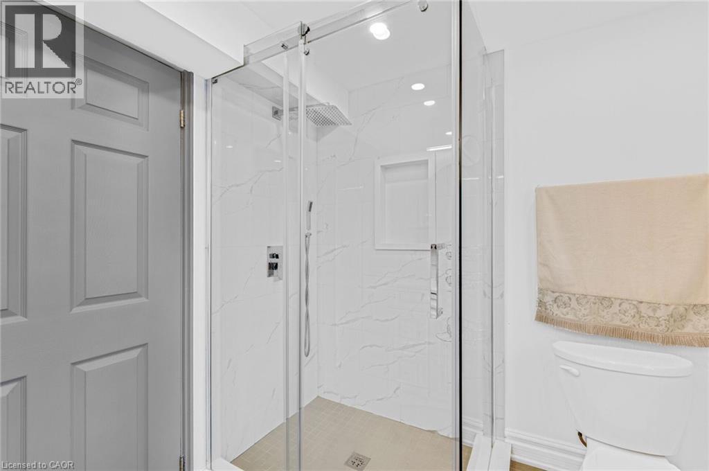 Glass-enclosed shower featuring white veined tile, a rain shower head, handheld shower fixture, and a built-in shower niche - 1 Galbraith Drive, Hamilton, ON - Indoor
