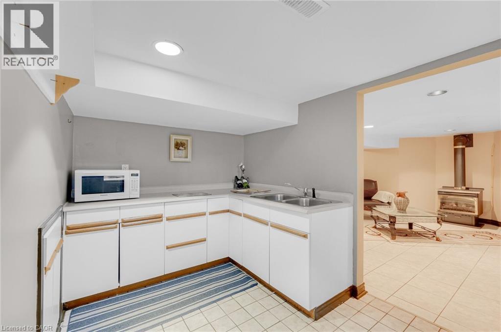 Lower-level kitchenette featuring white cabinetry, a double basin sink, and ample counter space - 1 Galbraith Drive, Hamilton, ON - Indoor Photo Showing Kitchen With Double Sink
