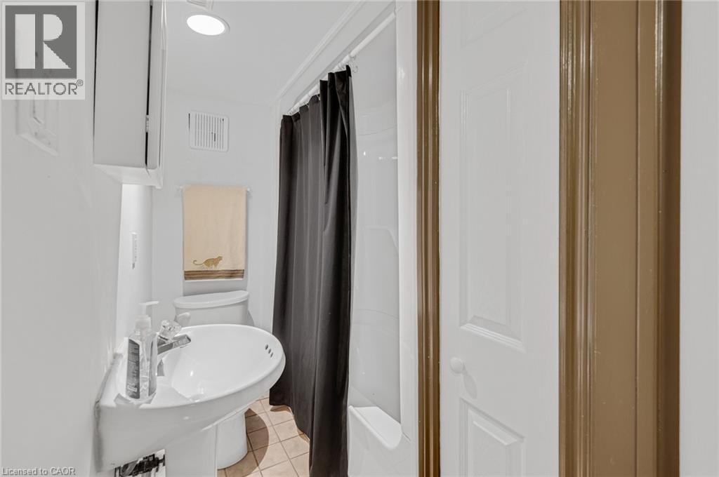 Bathroom featuring a pedestal sink, a toilet, and a shower-over-tub combination with a dark shower curtain - 1 Galbraith Drive, Hamilton, ON - Indoor Photo Showing Bathroom