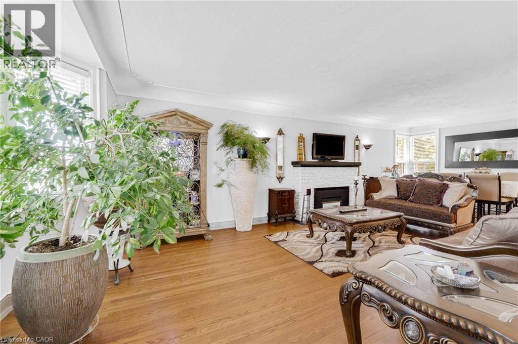 Spacious living area featuring wood-finish flooring, a white brick fireplace with a dark mantel, and recessed lighting - 1 Galbraith Drive, Hamilton, ON - Indoor Photo Showing Living Room With Fireplace