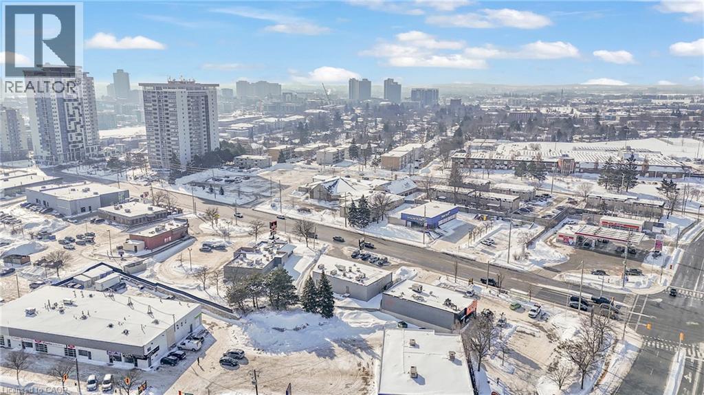 Urban landscape featuring multiple commercial buildings, paved roads, and distant high-rise structures - 402 King Street N, Waterloo, ON