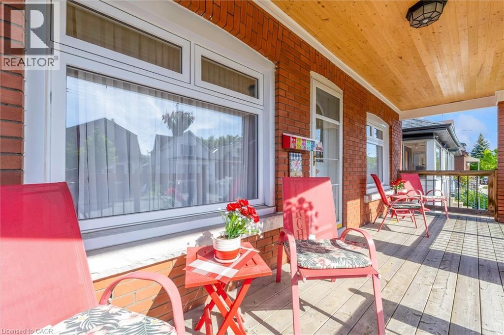 Inviting covered porch with a wood-finish ceiling, brick exterior, and wood-finish flooring - 121 Edgemont Street N, Hamilton, ON - Outdoor With Deck Patio Veranda