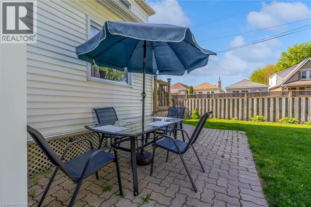 Paved patio area featuring interlocking brick, a perimeter fence, and a grassy yard - 121 Edgemont Street N, Hamilton, ON - Outdoor With Deck Patio Veranda With Exterior