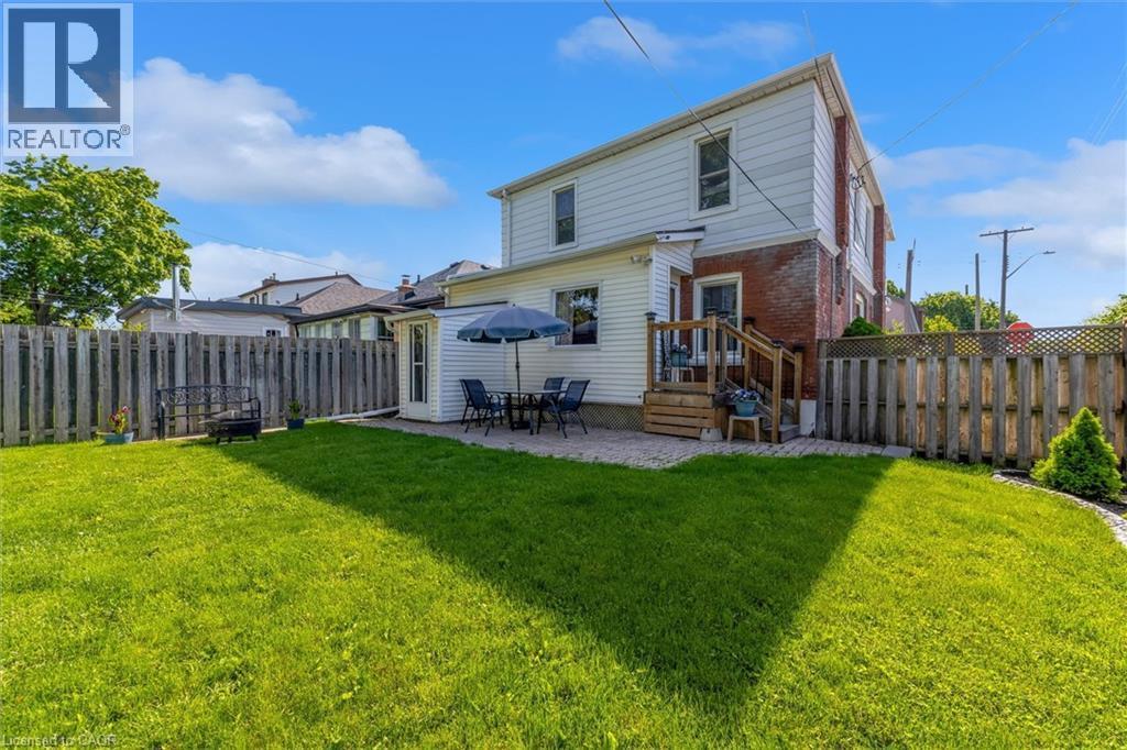 Expansive fenced yard featuring a large green lawn, a stone patio, and a wood deck with stairs - 121 Edgemont Street N, Hamilton, ON - Outdoor