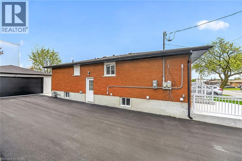 Brick exterior with a white entry door and multiple windows - 74 Victor Boulevard, Hamilton, ON - Outdoor With Exterior