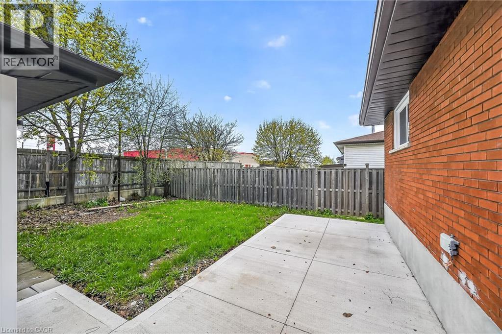 Private backyard featuring a concrete patio, a grass lawn area, and a wood privacy fence - 74 Victor Boulevard, Hamilton, ON - Outdoor