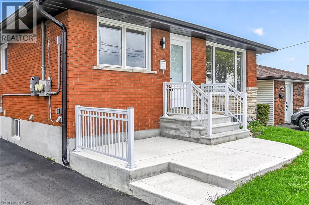 Brick exterior with white window frames and a white entry door - 74 Victor Boulevard, Hamilton, ON - Outdoor With Exterior