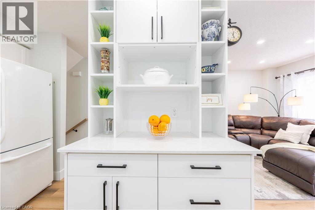 White built-in cabinetry with open shelving and closed storage, featuring matte black hardware, a light-toned countertop, and wood-finish flooring - 185 Highland Crescent Unit# 2, Kitchener, ON - Indoor Photo Showing Other Room