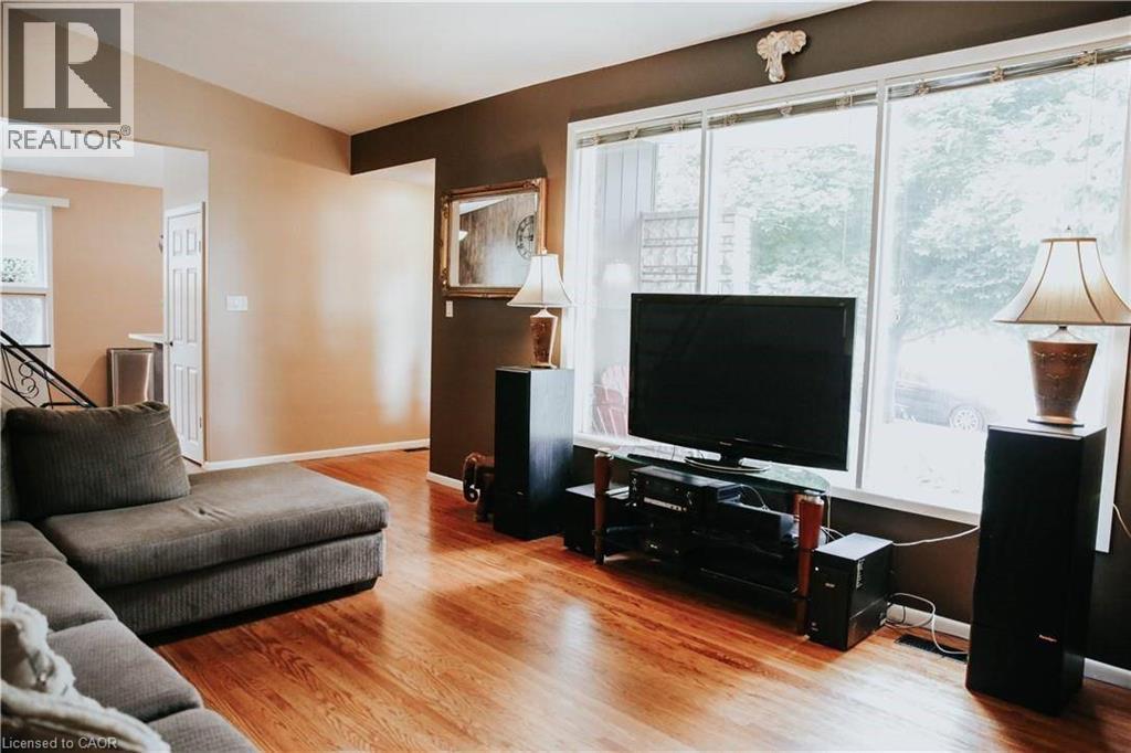 Open living area featuring wood-finish flooring, large windows, and an arched entry - 1 Vera Court, Hamilton, ON - Indoor Photo Showing Living Room