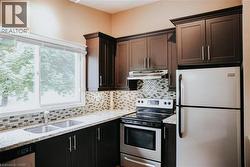 Kitchen featuring dark wood cabinetry, light-toned countertops, and a mosaic tile backsplash -