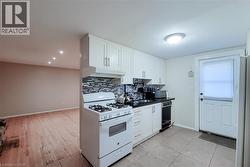 Kitchen featuring white cabinetry, a black countertop, and a tiled backsplash -