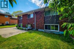Brick exterior with a partial concrete driveway and a manicured lawn -