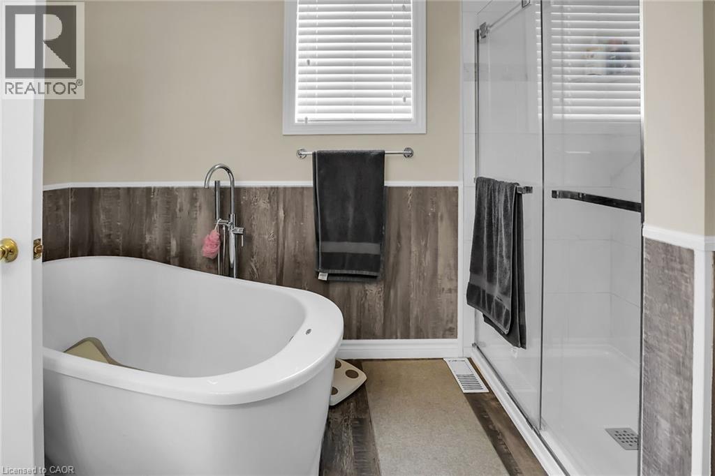Full bath with a soaking tub, a shower shower, wainscoting, and wood finished floors - 4432 Dennis Avenue, Beamsville, ON - Indoor Photo Showing Bathroom
